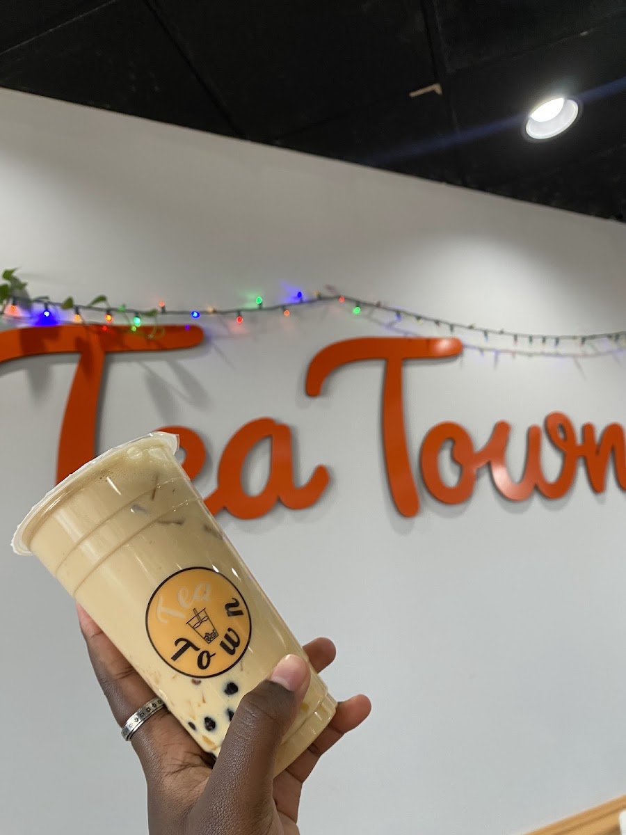 Boba milk tea in front of the Tea Town wall sign